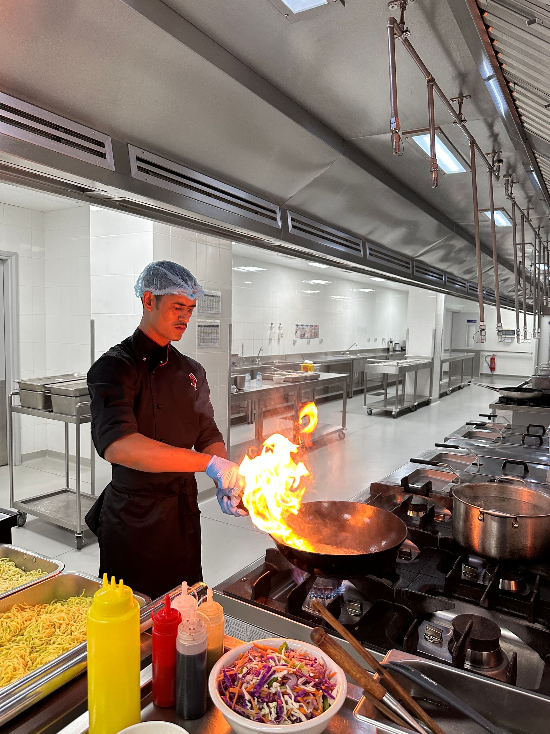 A chef cooking over a flaming wok